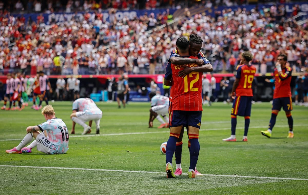 Spain players embrace while Belgium players sit on the pitch after the quarter-final