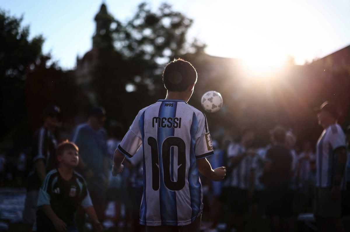 A young Argentina fan in a Messi number 10 shirt juggles a ball at sunset
